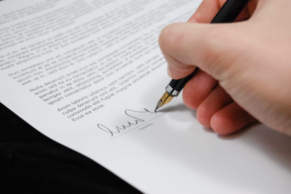 Eine Person unterschriebt einen Vertrag. Dies veranschaulicht einen Major Label-Vertrag.